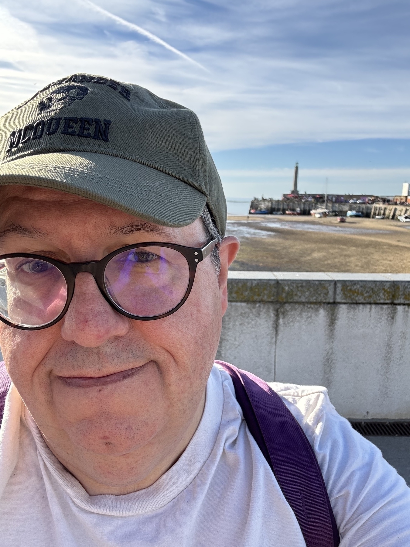 Middle aged bloke in hat and t shirt at the coast. 